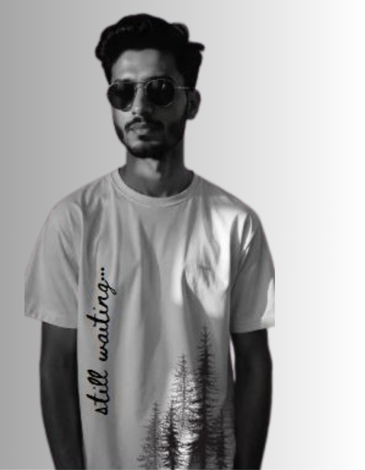White crew neck graphic t-shirt featuring black trees illustration on the left side and 'STILL WAITING' text in black typography on the right side.